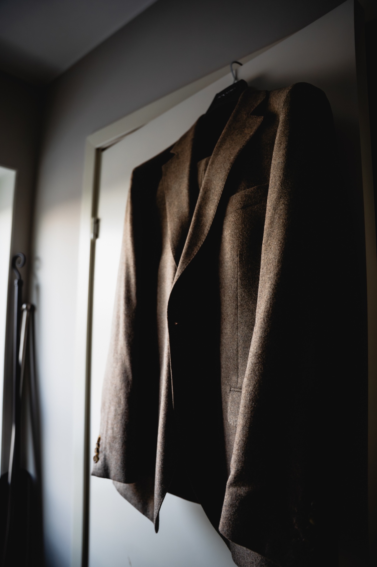 Groom's suit hanging in soft window light before the ceremony